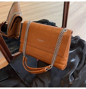 Detail of caramel brown quilted chain bag with silver logo text and sleek leather texture