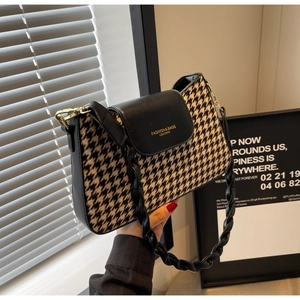 Detail of houndstooth fabric texture and black leather strap with gold metal buckle