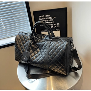 Detail of black quilted leather travel bag with silver hardware and adjustable strap