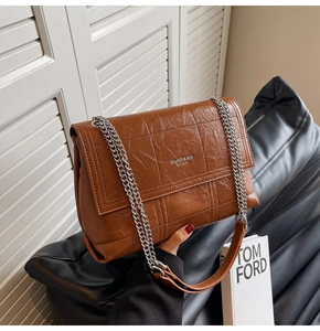 Detail of brown quilted leather shoulder bag with silver chain strap and brand logo
