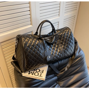 Detail of black quilted leather duffle bag with silver hardware and detachable strap