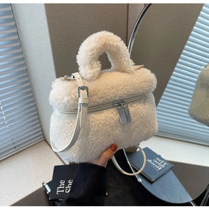 Détail d'un sac seau en peluche blanche avec double fermeture éclair et bandoulière