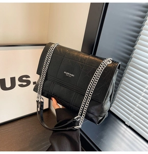 Close-up of black quilted PU leather shoulder bag with silver chain and white logo