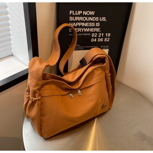 Detailed shot of brown canvas tote with side drawstring pockets and embroidered logo
