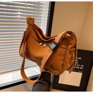 Detail view of caramel brown canvas tote bag featuring adjustable buckle and side pocket