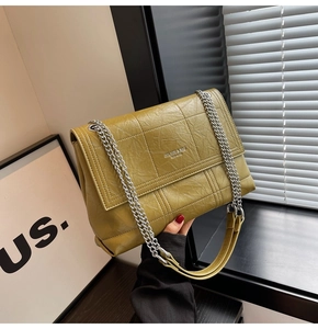 Detail of olive green quilted shoulder bag with silver chain strap and embossed logo