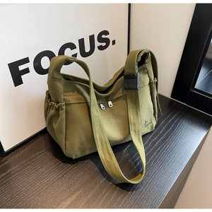 Detail of dark green canvas bag showing durable texture, zipper pocket and side flap pocket