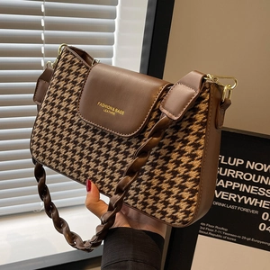 Brown leather and houndstooth crossbody bag with twisted handle shown in hand
