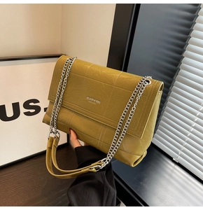 Close-up of mustard yellow quilted leather texture with silver chain and metal brand logo