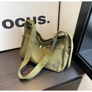 Detail of olive green canvas tote bag featuring double front zippers and side pocket