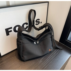 Detail of large black canvas tote with dual zippers and side pockets for storage