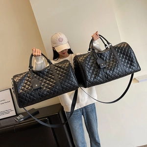 Large black quilted travel bag with dual handles and detachable shoulder strap in model shoot