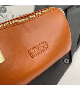 Detailed close-up of brown leather pillow bag with GuliDili logo and gold zipper
