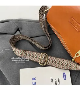 Detail of the wide ethnic pattern woven shoulder strap with gold metal buckle on orange bag