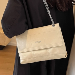 Large beige quilted flap bag with silver chain strap shown worn as a crossbody purse