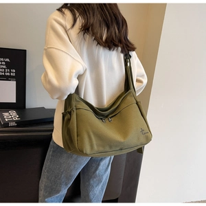 Detail of olive green canvas tote bag showing wide strap and double metal zippers
