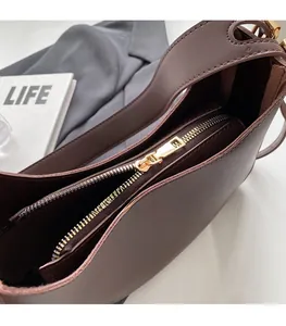 Detail of smooth gold zipper and wide puller on a dark brown vintage crossbody bag