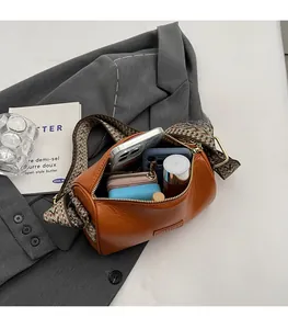 Internal view of brown leather cylinder bag showing capacity for phone and cosmetics