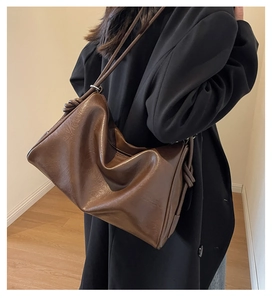 Detail of soft dark brown leather shoulder bag with side knot accents and sleek silhouette