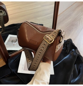 Detail of dark brown leather cylinder bag with colorful woven wide shoulder strap