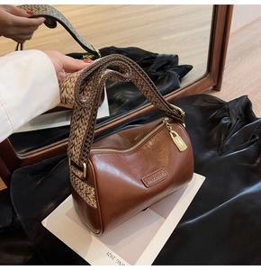Detail of vintage brown leather Boston bag with wide ethnic style woven shoulder strap