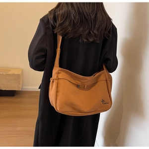 Detail of caramel canvas hobo bag showing pleated side design and wide shoulder strap