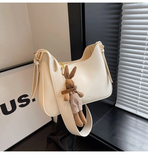 Detail of a creamy white PU leather shoulder bag featuring a cute brown plaid rabbit charm