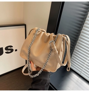 Dettaglio della borsa a secchiello plissettata beige con catena d'argento e tracolla