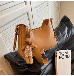 Detail of camel PU leather crossbody bag with fashion logo and a cute bunny charm