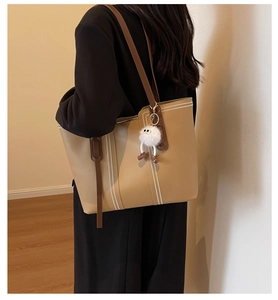 Side view of large khaki tote bag with white stitching and plush charm for daily commuting