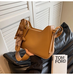 Close-up of camel hobo bag with wide strap and cute bunny plush charm detail