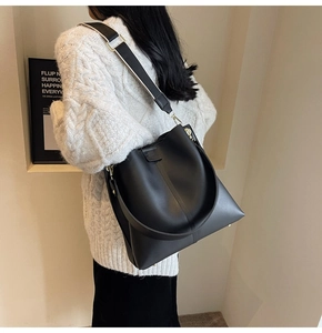 Detail of black leather bucket bag with striped woven strap and metal base studs