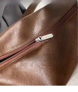 Detailed close-up of brown leather Boston bag featuring smooth silver zipper and stitching