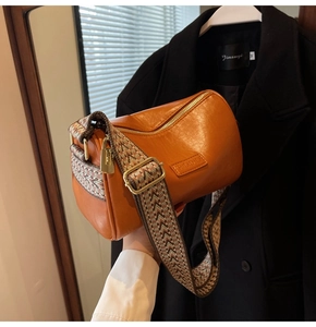 Detail of orange retro pillow bag with wide ethnic pattern strap and gold hardware