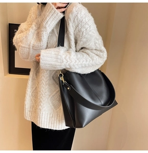 Detail of black leather bucket bag with stylish black and white woven strap and gold hooks