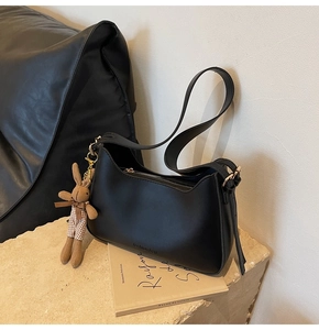 Detail of black semi-circle shoulder bag with fashion bag text and rabbit charm