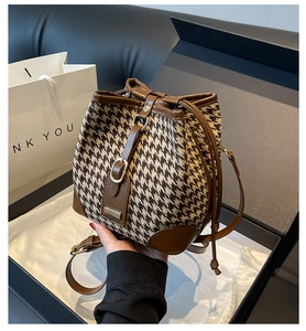 Close-up of houndstooth bucket bag featuring leather drawstring and gift packaging