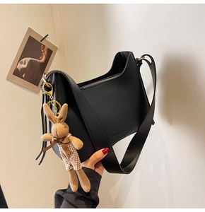 Close-up of black matte half-moon shoulder bag with fashion bag lettering and rabbit charm
