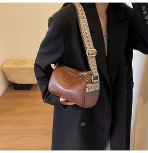 Detail of vintage brown cylinder bag with ethnic style wide woven shoulder strap on model