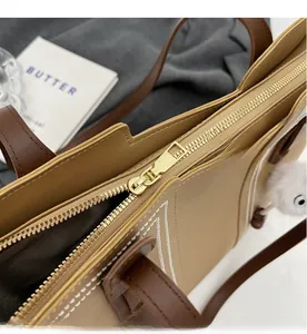 Close-up of smooth gold metal zipper and stitching on beige tote bag with a plush charm