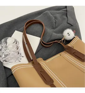 Top view of large khaki tote bag with brown straps and white plush eye charm detail