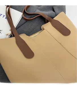 Close-up of contrast stitching and gold metal zipper on beige faux leather tote bag