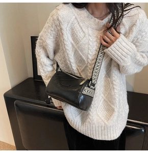 Detail of black cylinder bag featuring a retro geometric woven wide shoulder strap