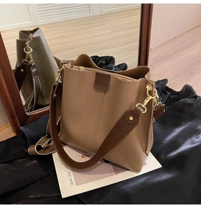 Detail view of khaki leather bucket bag with wide strap and embossed brand logo