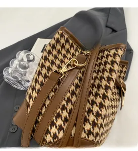 Detail of houndstooth bucket bag with brown leather trim and golden metal hardware