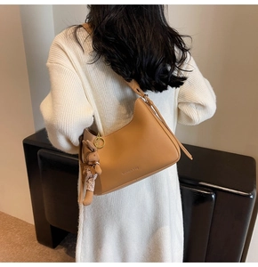 Detail of camel crescent shoulder bag with a cute rabbit charm and fashion bag print