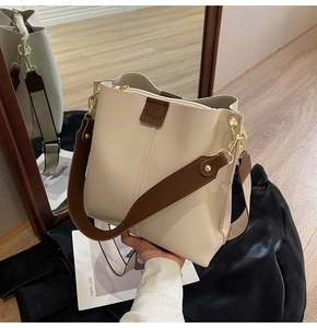 Detailed close-up of cream leather bucket bag with wide strap and mirror reflection