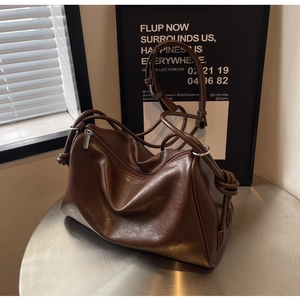 Detail of vintage brown PU leather handbag with fine texture and knotted shoulder strap