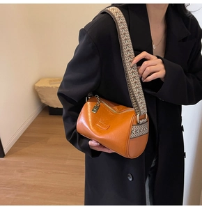 Close-up of caramel leather Boston bag with vintage bohemian wide strap detail