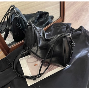 Detail of black leather Boston bag with side knot tassel and silver metal zipper closure